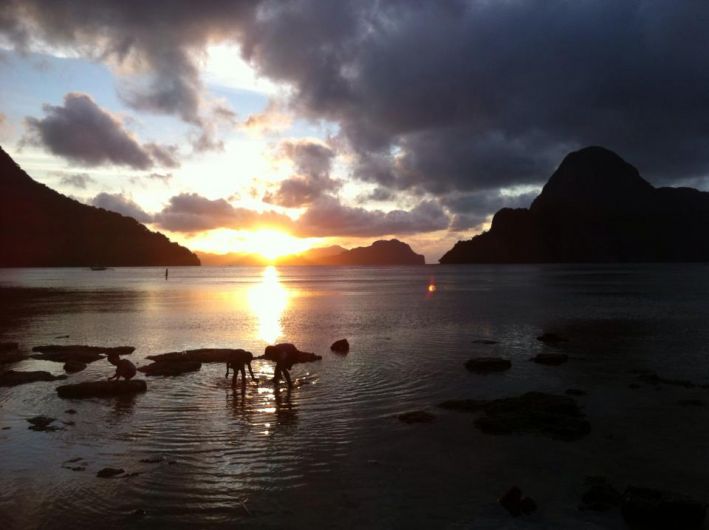 Children playing in the water at sunset in El Nido, Philippines.
